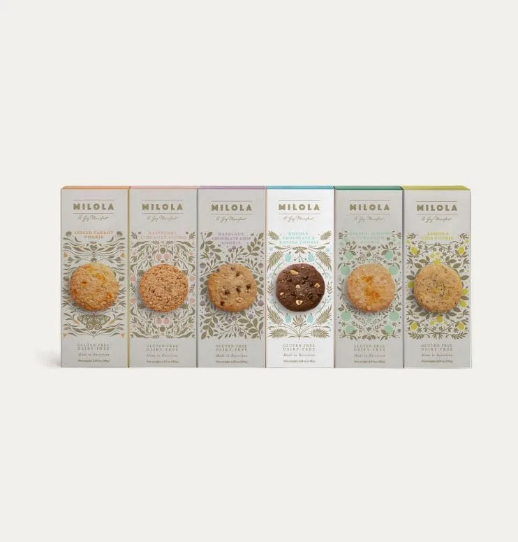 Foto de las cajas de los seis sabores de galletas sin gluten de Milola con la galleta vegana de doble chocolate y platano resaltada.